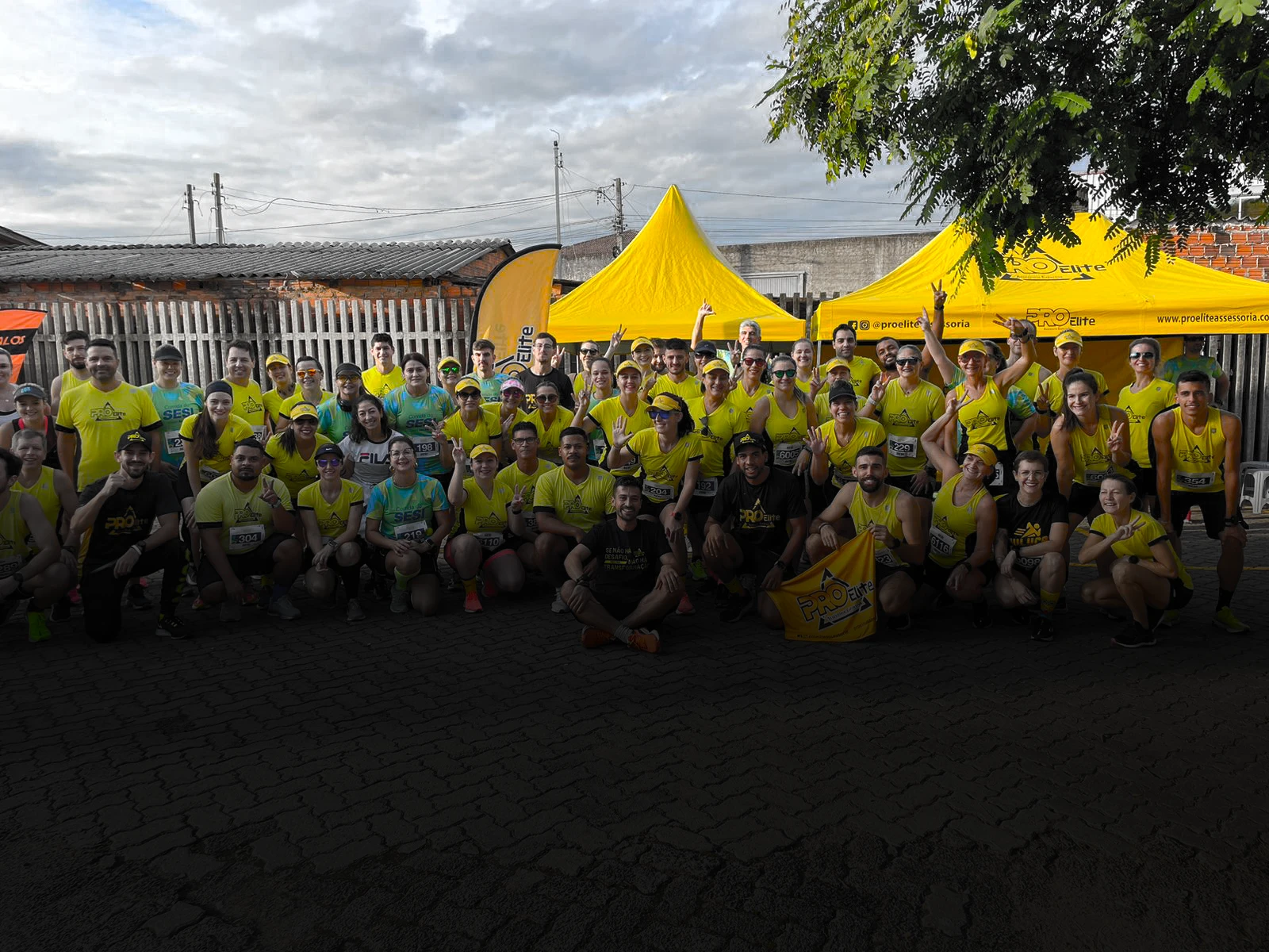 Turma da ProElite reunida em frente às tendas amarelas da assessoria no dia de uma prova